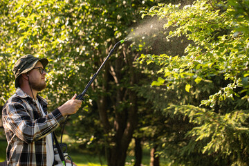 Garden sprayer. The gardener sprays tree in the garden with a spray bottle. Pest control concept....
