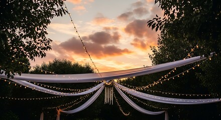 A breathtaking canopy of fabric adorned with soft lighting, set against a vibrant sunset sky. The scene exudes romance and elegance.