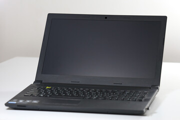 Open black laptop with a blank screen placed on a white surface. Portable computer device for office work, studying, digital communication, and creative tasks in modern lifestyle.