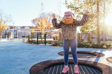 Girl with Down syndrome jumping on playground trampoline