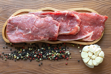 Close-up of beef tenderloin on a wooden board with spices and peppers