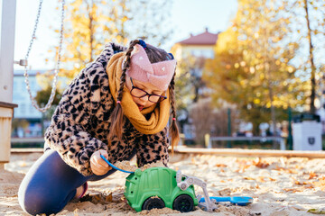 Curious girl with Down syndrome playing with toy truck in sandbox