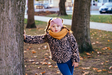 Curious girl with Down syndrome leaning on tree