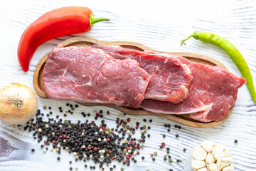 Close-up of beef tenderloin on a wooden board with spices and peppers