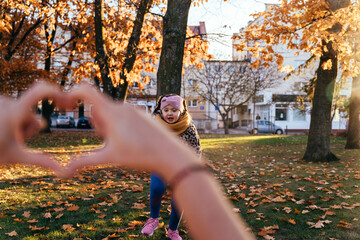 Playful girl framed in heart hands gesture