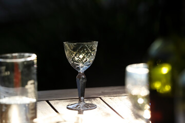 Aesthetic outdoor table setting with wine bottle and glass. No people, dark background, reflections