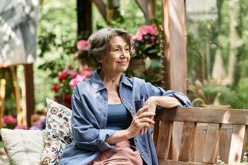 Senior woman enjoys tranquility in a lush garden filled with vibrant flowers and greenery