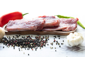 Close-up of beef tenderloin on a wooden board with spices and peppers