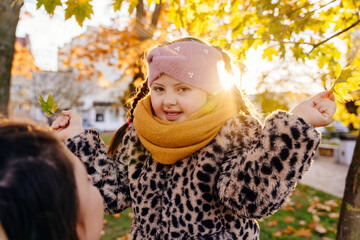 Cheerful girl with Down syndrome holding autumn leaves in sunlight