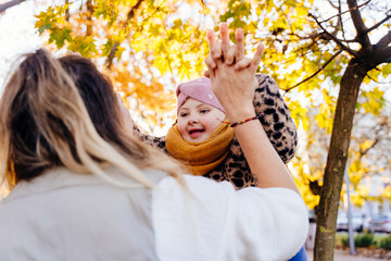Smiling girl with Down syndrome holding hands in autumn park