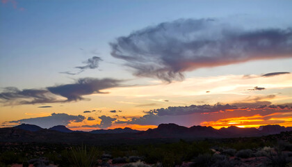 Naklejka premium Vibrant Sunset Over Desert Landscape with Colorful Clouds and Mountains