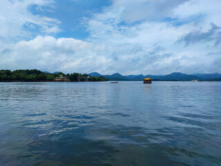 The good view of the west lake (Xi Hu) with the yellow boat and the blue sky.
