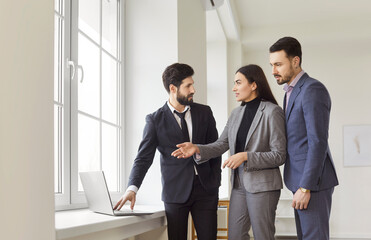 Portrait of confident man professional realtor standing with couple clients in modern new apartment...