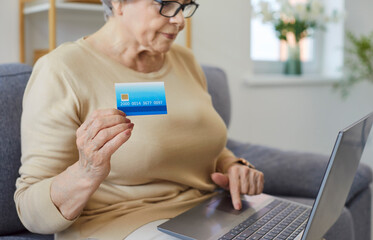 Old senior mature bank client woman making online payment holding plastic card, credit card, paying...