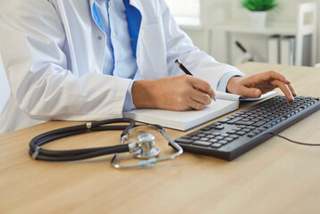 Medical professional doctor working, male nurse at office desk, using keyboard consulting notebook, professional communication and information management, clinical or administrative help to patient 
