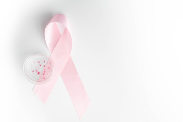 Breast cancer research concept, glass petri dish and pink awareness ribbon isolated on white...
