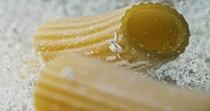 Macro of Rigatoni Pasta Falling in Slow Motion on Floury Surface , Golden Texture, and Traditional Italian Cuisine Ingredients Captured in High-Detail for Culinary and Food Concepts Delicious Meal
