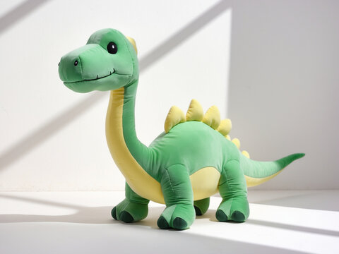 Cute green dinosaur stuffed animal with a yellow belly and friendly smile. This adorable plush toy is isolated on a white background, perfect for children or playtime concepts.