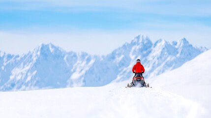 Snowmobiler enjoys a sunny day riding through majestic snow covered mountains