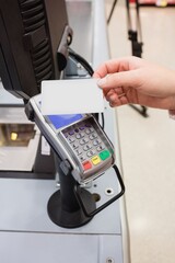 Cropped image of person holding credit card with reader