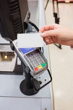 Cropped image of person holding credit card with reader