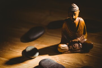 Wooden Buddha statue in circle made from pebbles