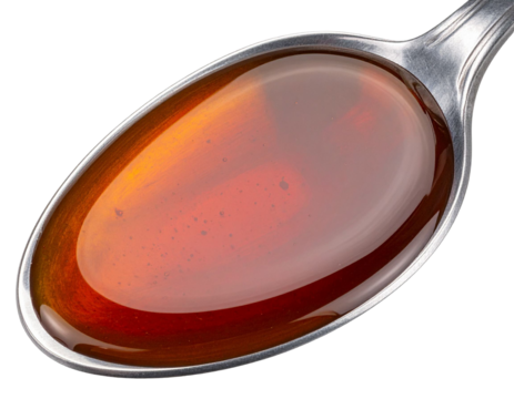 Close up of golden brown date syrup dripping from silvery spoon, highlighting viscous texture and sweet culinary ingredient