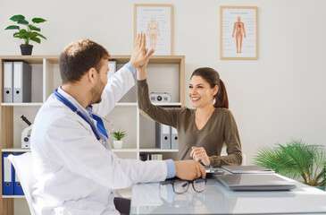 Happy woman patient gives high five to doctor or nurse during consultation or conversation in...