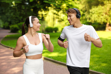 Sporty couple with headphones running in park