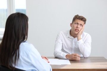 Young man complaining to woman at wooden table indoors