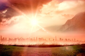 Flat design sun is radiating over grass field with modern skyline, misty mountain and tinted clouds © vectorfusionart