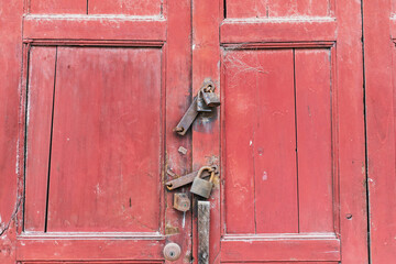 An old red wooden door locked with a lock