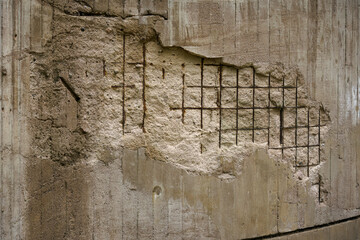 Concrete wall with surface erosion, revealing internal rebar structure