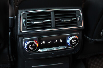 Rear-seat climate control panel with dual-zone digital temperature display, surrounded by black leather and chrome-trimmed air vents.