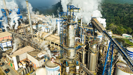 Aerial drone view of a pulp and paper industry with smoke clouds rising from boilers and chimneys, illustrating pollution and environmental damage from industrial activity