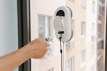Robotic window cleaner operated by maintenance worker, performing precision cleaning of skyscraper exterior. Concept of convenience and effectiveness in everyday household chores, maintenance tasks. © dikushin