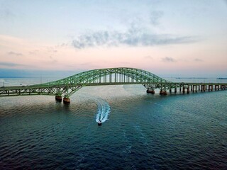 Obraz premium Aerial view of a boat under a bridge at sunset.