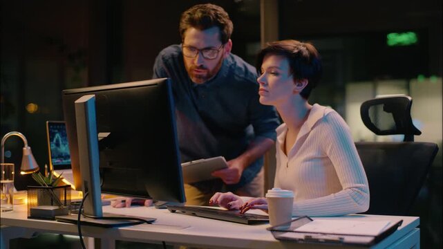 Business woman man in night office crypto online computer trading cooperation businessman businesswoman Caucasian colleagues co-workers employees teamwork mentoring boss intern overtime evening work