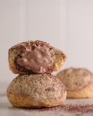 Delicious chocolate-filled cream puff with a light and airy choux pastry, generously dusted with cocoa powder. The close-up composition highlights the rich, creamy texture.