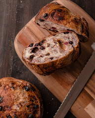 Artisanal rustic bread loaf with dried berries and nuts, sliced on a wooden cutting board. Freshly baked crust with a golden brown texture, perfect for bakery and food photography © IndraGunawan