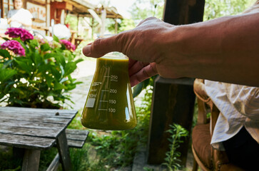 Person is holding a green liquid in a beaker