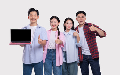 Obraz premium Four smiling Asian friends promote a laptop and give thumbs up against a white background