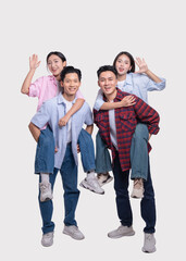 Fototapeta premium Two men giving women piggyback rides all smiling and waving isolated on a white backdrop