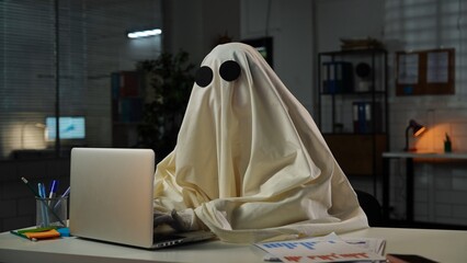 Ghost in a Sheet Typing on Laptop in Dimly Lit Office