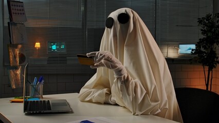 Person in Ghost Costume with Credit Card at Office Desk