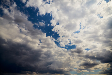 Cumulus clouds in the sky with sunlight on the clouds, clouds before a change in weather, cloudy background, texture of clouds on the blue sky.