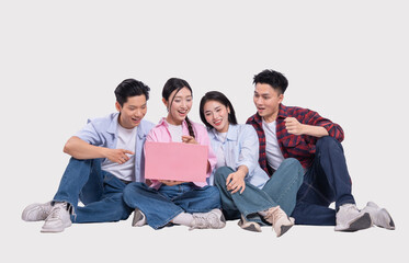 Enthusiastic young adults gather smiling and watching a laptop screen sharing a joyful moment