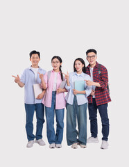 Obraz premium Four young people in casual clothes smile and point to the side while holding their books