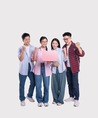 Obraz premium Excited group of young people celebrating achievement while looking at a laptop together