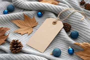 Blank kraft tag on knitted gray sweater with autumnal decor
